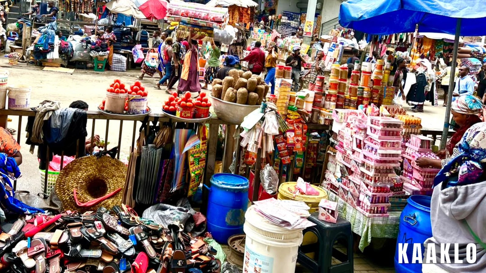 Traders and goods at Makola Market in Accra: stalls with shoes, tomatoes, yams and household goods.