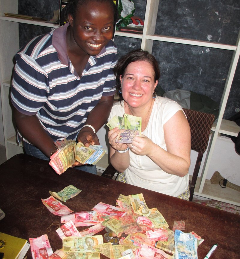 Two people counting Ghana cedi banknotes on a table in Hohoe, Volta Region.