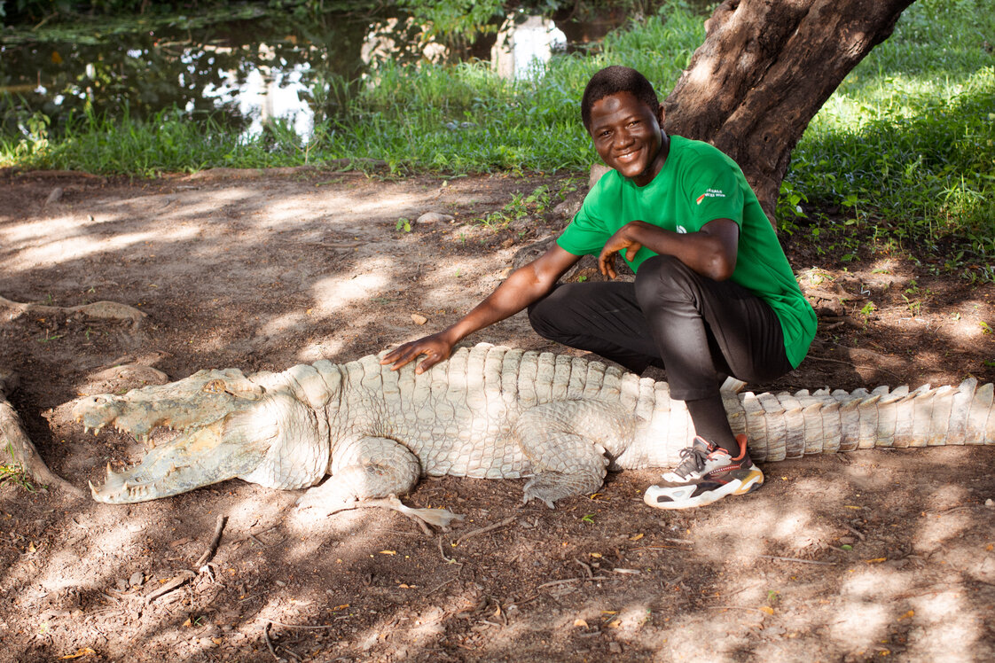 A visitor beside one of Paga's famous crocodiles at the town's crocodile pond.