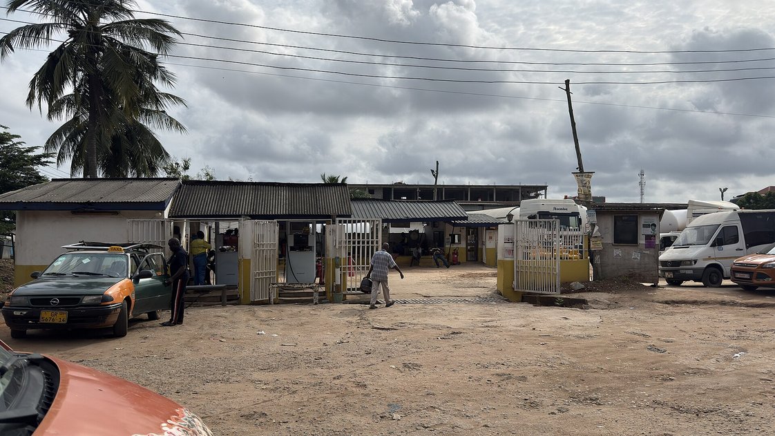 A small gas filling station in Ghana with a taxi parked outside.